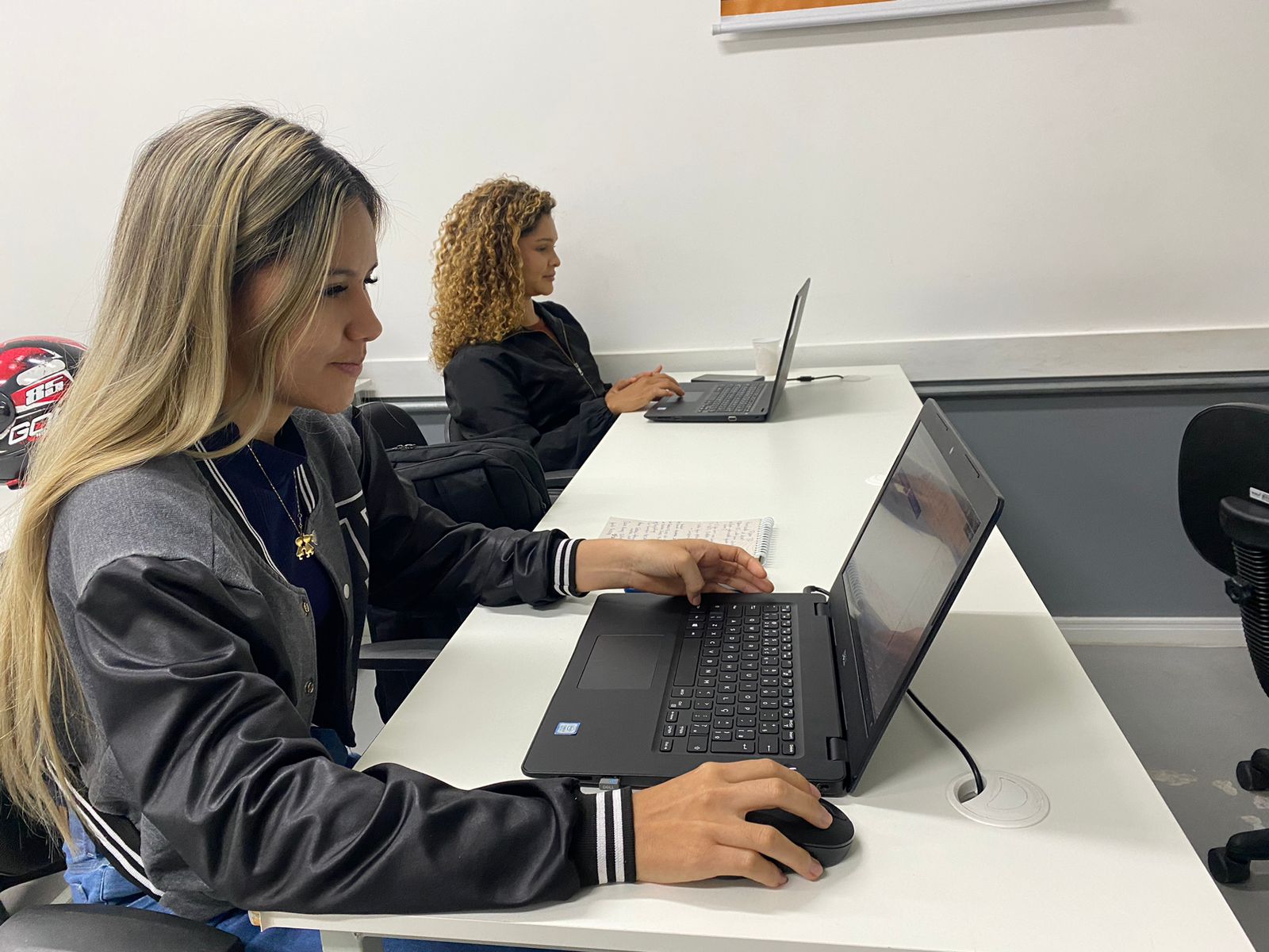 Alunas praticando em notebooks durante treinamento